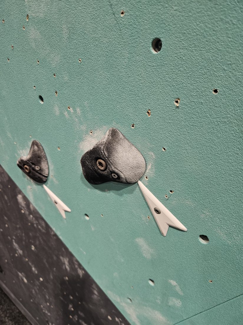 White printed route marker on a teal wall panel at Beta Climbing Gym.