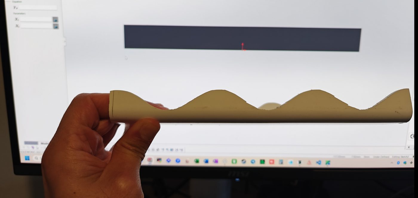 Profile-matched part held in front of a CAD model.