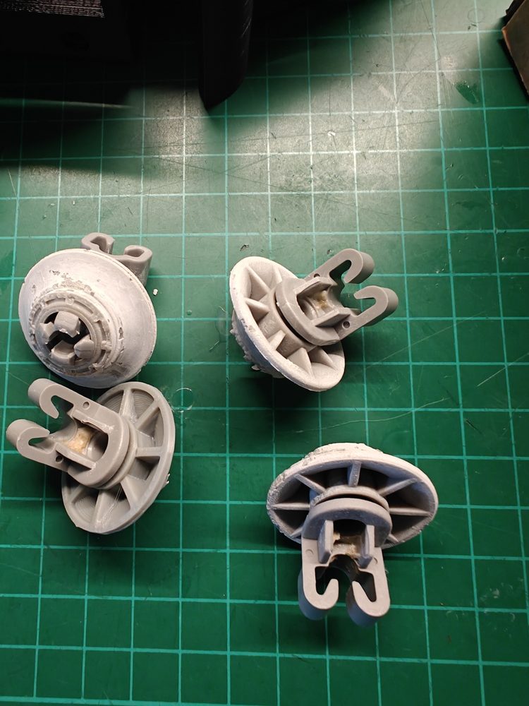 Dishwasher wheel components on a cutting mat for reverse engineering.