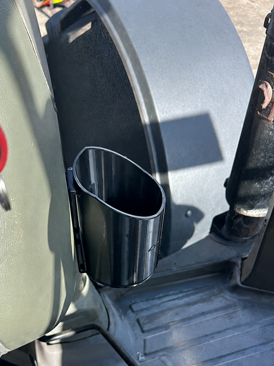 Black printed bottle holder mounted beside the tractor seat at Goble Contracting.