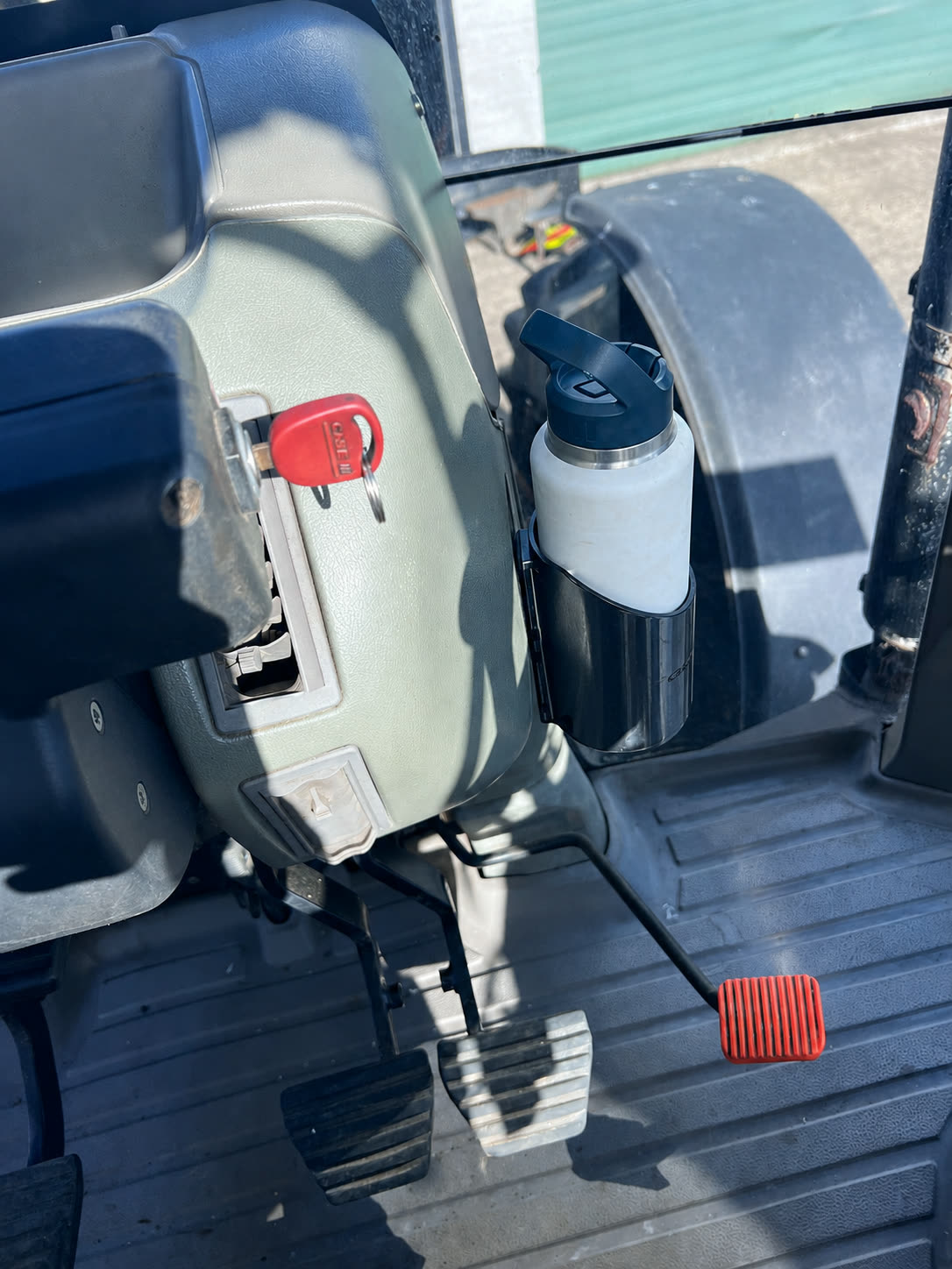 White drink bottle sitting in the black Quality3Ds holder beside a tractor seat.