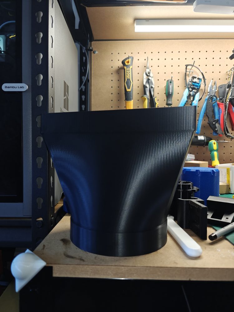 Large black duct adapter prototype on a workshop bench.