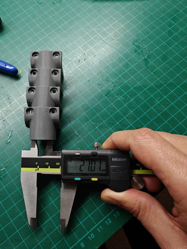 3D printed bracket being measured with digital calipers.