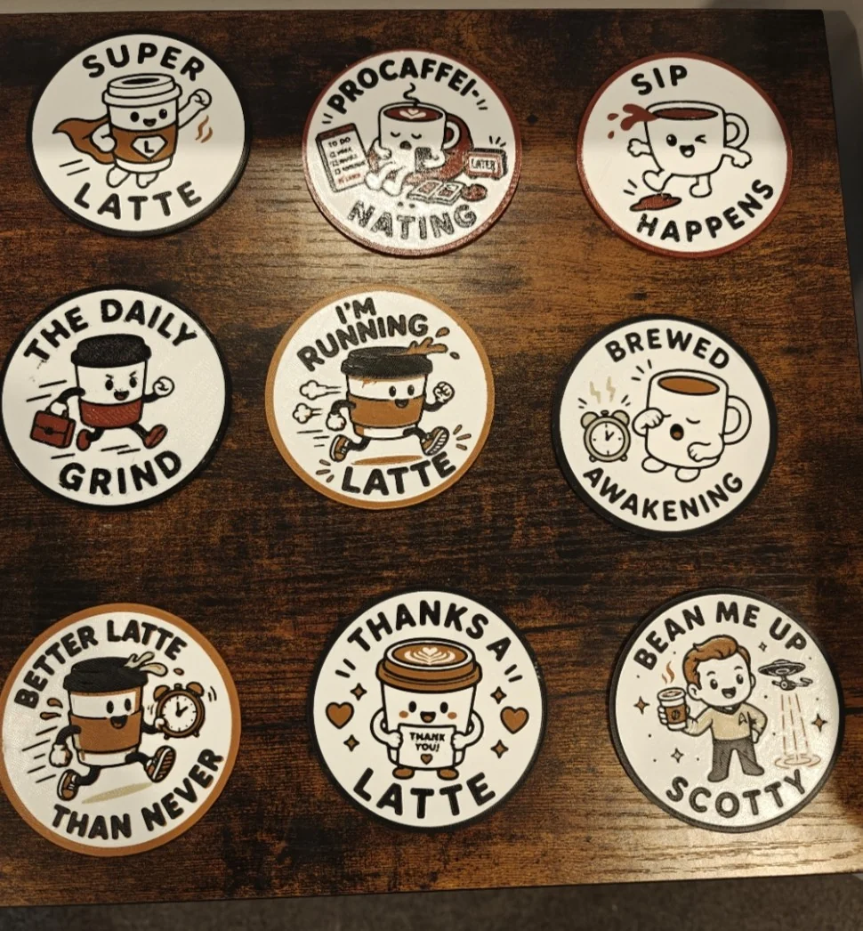 Nine finished Quality3Ds coffee-themed coasters arranged on a wood-grain surface.