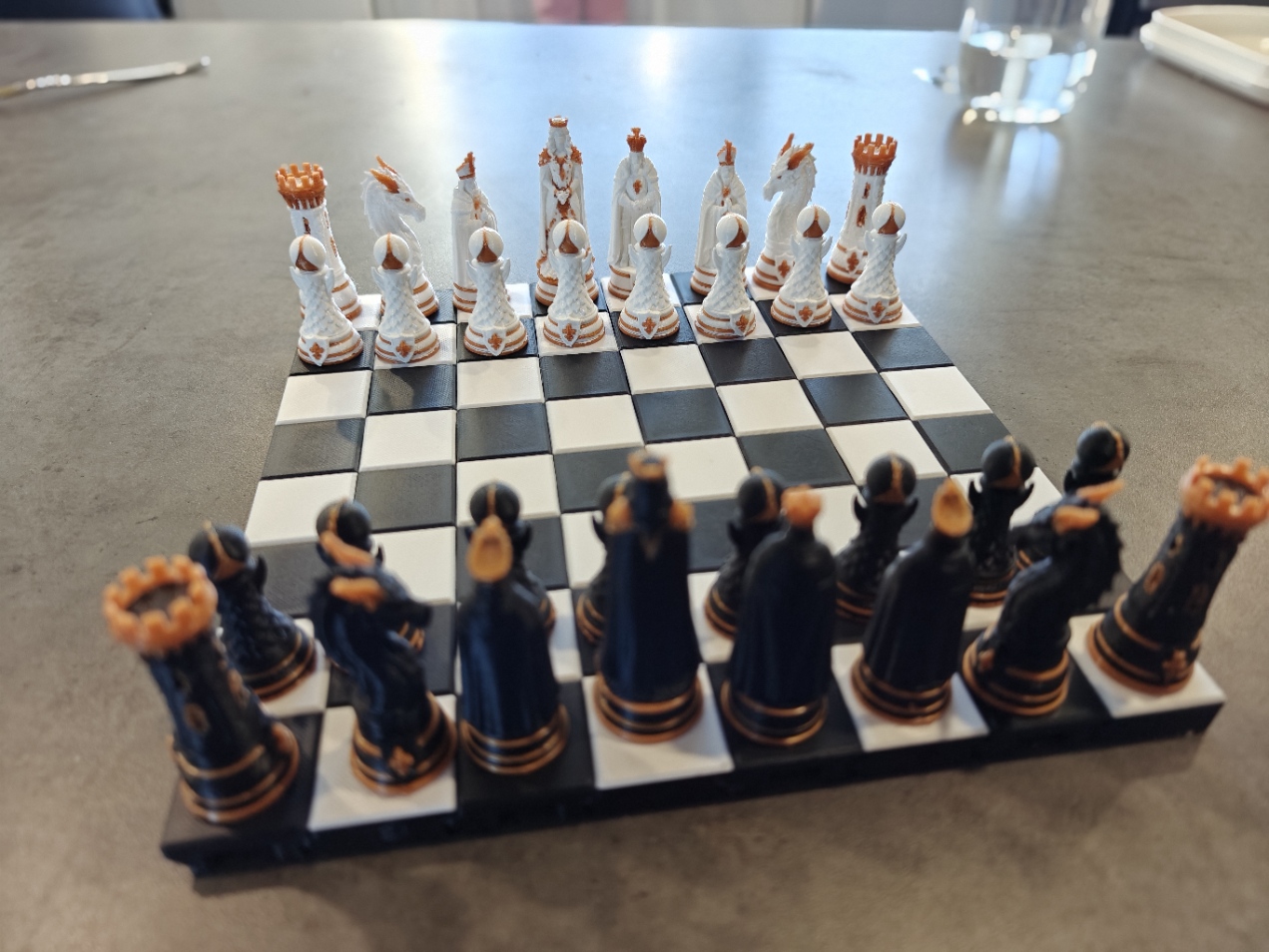 Quality3Ds original fantasy chess pieces arranged on a black and white board with gold accents.