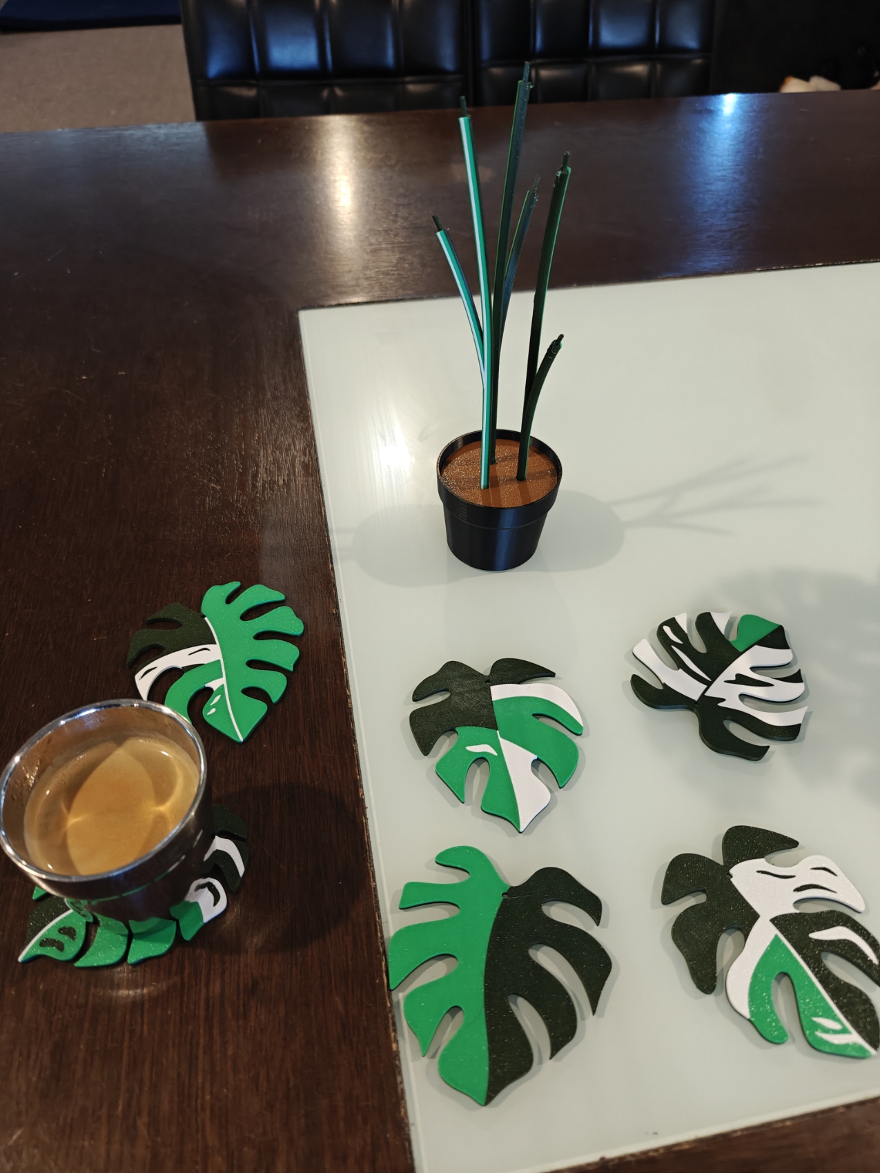 Printed Monstera variegata plant and six leaf coasters arranged on a table.