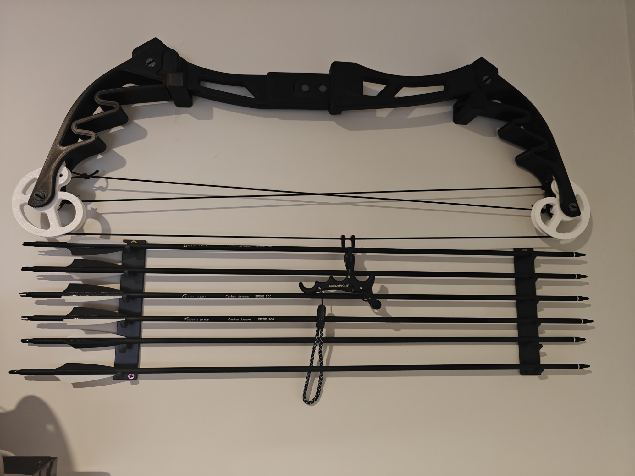 Large assembled compound bow print displayed on a wall with arrows below.